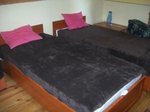 2 Betten mit schwarzen Bettdecken und rosa Kissen in der Unterkunft Domek Anna in Turawa