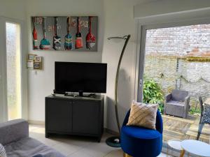 a living room with a tv and a blue chair at Maison avec jardin, calme et ensoleillée à 2 minutes du centre-ville in Cabourg