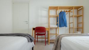 a bedroom with two beds and a red chair next to a desk at Casa BON BON in Triscina