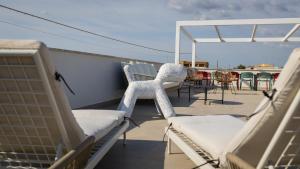 a balcony with chairs and tables on a roof at Casa BON BON in Triscina
