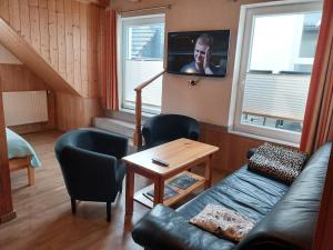 a living room with a couch and a tv at Ferienwohnung - Landhotel Waldschlößchen in Sohland