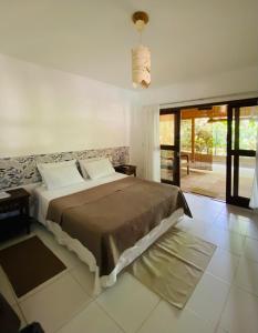 マラウにあるFlat Ewa Condomínio beira-mar Varanda Piscinaのベッドルーム1室(大型ベッド1台、スライド式ガラスドア付)