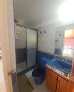 Un baño con un inodoro azul y un lavabo. en Casa con piscina privada, en Melgar