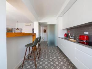 a kitchen with white cabinets and a counter with stools at Apt. dos Correios in Lagos