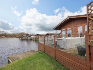 a house on a dock next to a body of water at Otters Reach in Carnforth