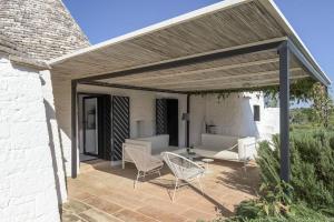 een patio met stoelen, een bank en een tafel bij Cocotrullo in Cisternino