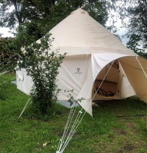a white tent sitting in the grass next to a tree at Herredet - The Shire in Fejø