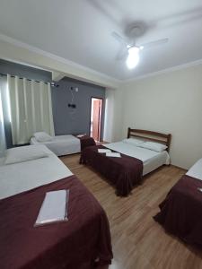 a hotel room with three beds and a ceiling fan at Pousada Estrela Mares in Cabo Frio