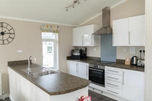 a kitchen with white cabinets and a sink at Croyde Bay Hotel or Self Catering in Croyde