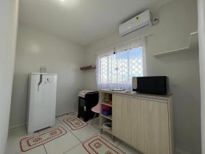 Elle comprend une petite cuisine avec un réfrigérateur et une fenêtre. dans l'établissement Apartamento Studio Climatizado, à Chapadão do Sul