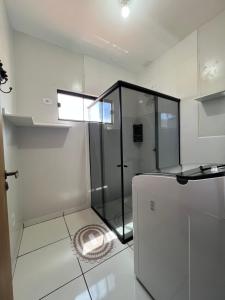 une salle de bain blanche avec une douche et un lavabo dans l'établissement Apartamento Studio Climatizado, à Chapadão do Sul