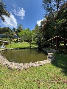a small pond in the grass with a gazebo at Sítio Mairiporã-Piscina Aquecida in Mairiporã +46 photos
