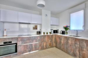 una cucina con elettrodomestici bianchi e armadietti in legno di superbe 3 chambres proche palais et croisette dag13 a Cannes