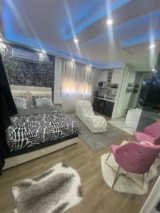 バニャ・コヴィリャチャにあるLove spa apartmanのベッドルーム1室(白黒のベッド1台、ピンクの椅子2脚付)