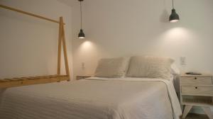 a bedroom with a bed with white sheets and a dresser at Cabañas Aire Fresco in Mar del Plata