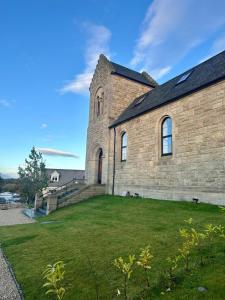 an old brick church with a grass yard at The Bell Tower in Bonnybridge