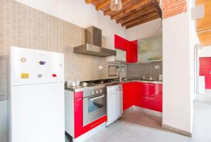 a kitchen with red cabinets and a white refrigerator at Moka Rooms and Flats in Pisa