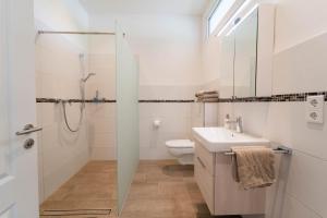 een witte badkamer met douche en wastafel bij Ferienwohnung Marder in Münster