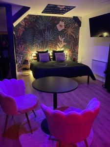 a bedroom with a bed and two chairs and a table at Love room Spa "Trésor des Anges" in Rouen