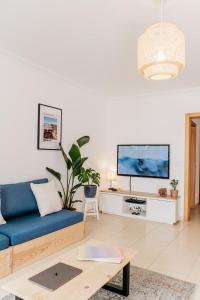 a living room with a blue couch and a tv at Green House in Baleal