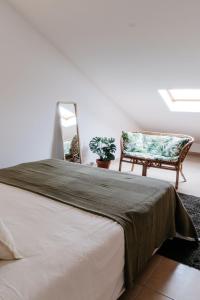 a bedroom with a bed and a chair and a mirror at Green House in Baleal