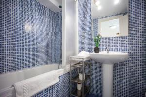 W wyłożonej niebieskimi kafelkami łazience znajduje się umywalka i lustro. w obiekcie Fuencarral Apartments w Madrycie +37 zdjęć