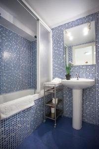 W wyłożonej niebieskimi kafelkami łazience znajduje się umywalka i wanna. w obiekcie Fuencarral Apartments w Madrycie