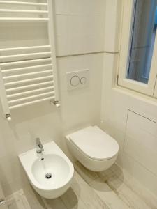 a white bathroom with a toilet and a sink at Attico 101 in Pistoia