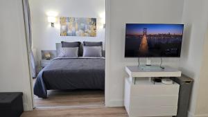 a bedroom with a bed and a flat screen tv at Suite Prestige Paris-La Défense Balcon-Terrasse in Courbevoie