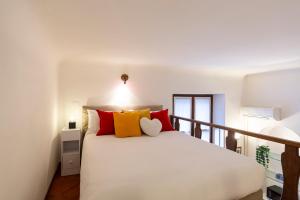 ein Schlafzimmer mit einem weißen Bett mit roten und gelben Kissen in der Unterkunft Monte Nero UP&DOWN in Mailand