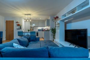 Una sala de estar con un sofá azul y un televisor. en Modern flat w/ balcony & projector cinema, en Bristol