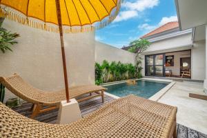 a patio with chairs and an umbrella next to a swimming pool at Chic Brand New 2BDR Villa with Luxe Pool - The Ultimate Canggu Escape! in Kerobokan