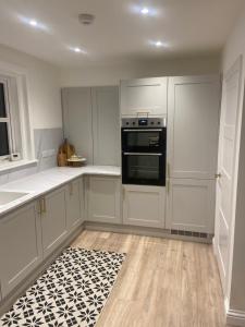 une cuisine avec des armoires blanches et un four noir dans l'établissement Halfred House, à Wick
