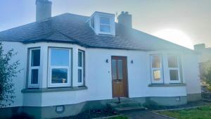 une maison blanche avec une porte et des fenêtres marron dans l'établissement Halfred House, à Wick