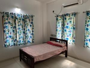 a small bedroom with curtains and a small bed at Safari Homestay, Malayattoor in Kodanad