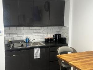 a kitchen with black cabinets and a sink and a table at Town Centre Cosy Flat in Merthyr Tydfil +6 photos
