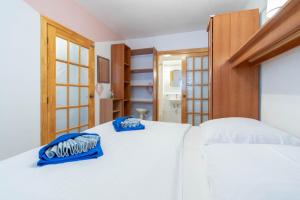 ein Schlafzimmer mit einem weißen Bett mit blauen Kissen darauf in der Unterkunft Apartment K & K in Baška Voda