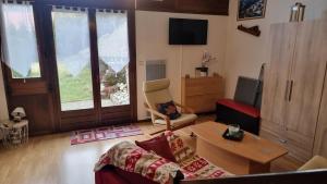 een woonkamer met een bank en een tafel bij Chez Mady - Terrasse, Vue Montagne & Proche Ski in Bussang