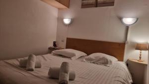 een slaapkamer met een groot wit bed met twee paar benen erop bij Chez Mady - Terrasse, Vue Montagne & Proche Ski in Bussang