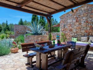 un patio con mesa de madera, sillas y pared de piedra. en Villa Oxa Dreamland, en Stari Grad