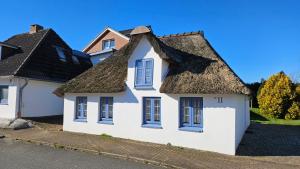 a white house with a thatched roof at Holiday Homes Buchholz in Büsum