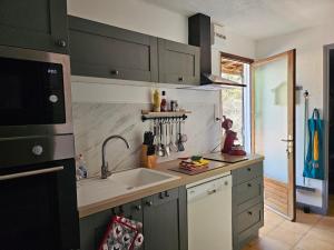 a kitchen with gray cabinets and a sink and a window at LA PETITE MAISON DU LAC in Biscarrosse