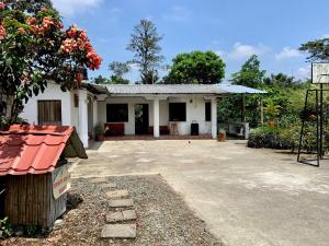 une petite maison blanche avec un toit rouge dans l'établissement Casa de Campo - Jacuzzi y Río en Santo Domingo, à Santo Domingo de los Colorados