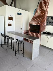 a kitchen with a table and chairs and a brick wall at Sonho de Verão in Paripueira