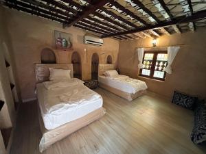 una stanza con due letti e una finestra di Al-Ghanima Rest House a Al Ḩamrāʼ