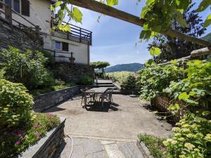 a patio with a table and chairs in a garden at Wild Valley Ticino Villa in Valle Onsernone in Auressio +22 photos
