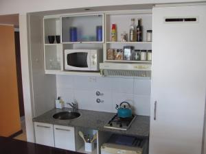 a small kitchen with a sink and a microwave at Apartamento en Cetro Real Condominium & Suites in Rosario