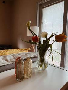 a vase with flowers on a table next to a bed at Bed and Breakfast CASA MANU in Loro Ciuffenna