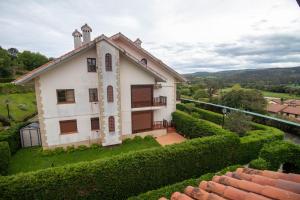 a white house with a green hedge at Ático espectacular Comillas a 2 Km in Liandres