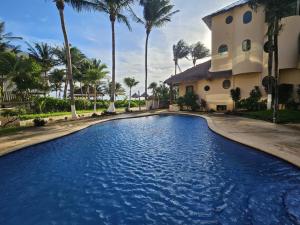 a swimming pool in front of a house with palm trees at Villas Kaàn in Puerto Morelos